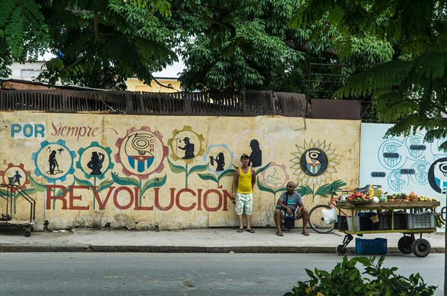 Two men standing near the wall with a mural Guille Álvarez (@guillealvarez)